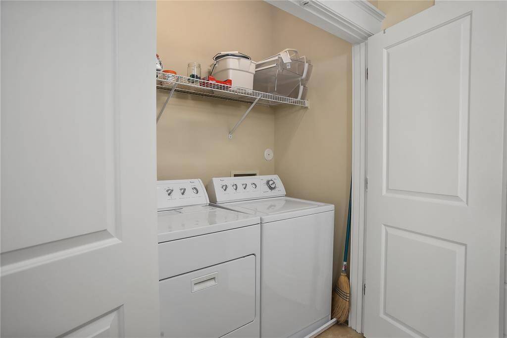 Enjoy the ease of a full-size washer and dryer, along with built-in shelving for added storage in this private laundry space.