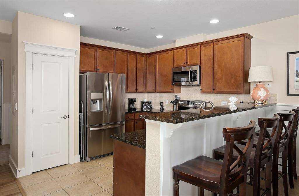 Designed for both style and function, this kitchen boasts granite countertops, custom cabinetry, stainless steel appliances, and a raised breakfast bar for casual dining.