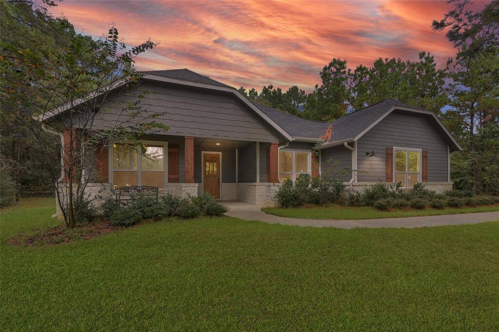 This stunning home features a modern design with a welcoming front porch, surrounded by lush greenery.