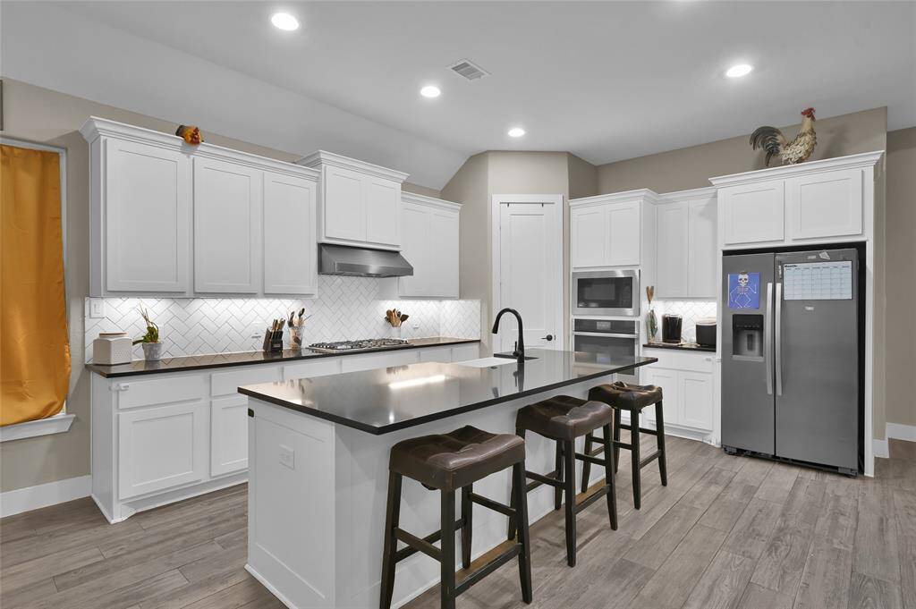 The kitchen features a spacious island, gas cooktop, built-in wall oven, and elegant under-cabinet lighting.