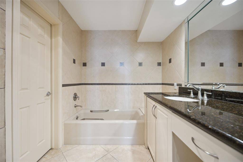 Granite countertops, double sinks, vanity area, and large soaking tub