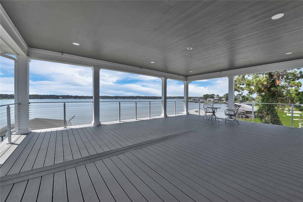 This photo showcases a spacious covered deck with a stunning waterfront view. It features a sleek railing, ample space for outdoor furniture, and a serene setting perfect for relaxation and entertaining.