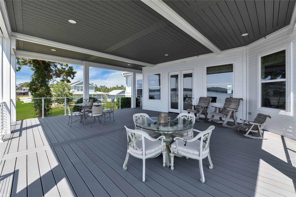 This spacious covered deck features elegant outdoor seating and charming rocking chairs. It offers a great view of the surrounding neighborhood and is perfect for relaxing or entertaining guests.