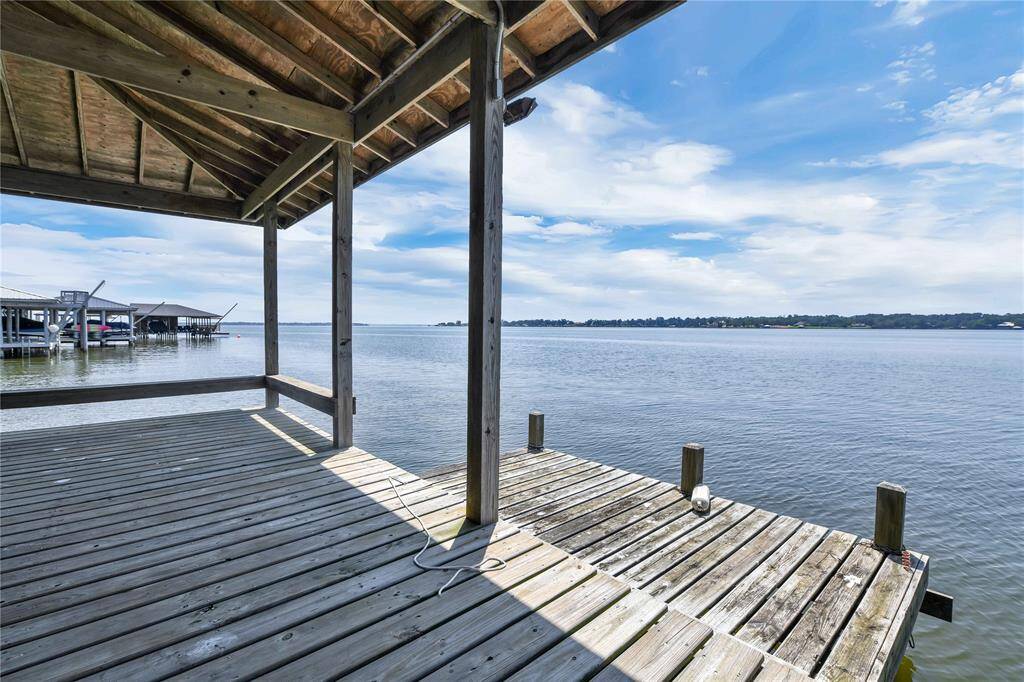 This photo showcases a wooden dock with a covered area overlooking a serene lake, offering picturesque water views and a peaceful setting. Perfect for lakeside relaxation or boating activities.