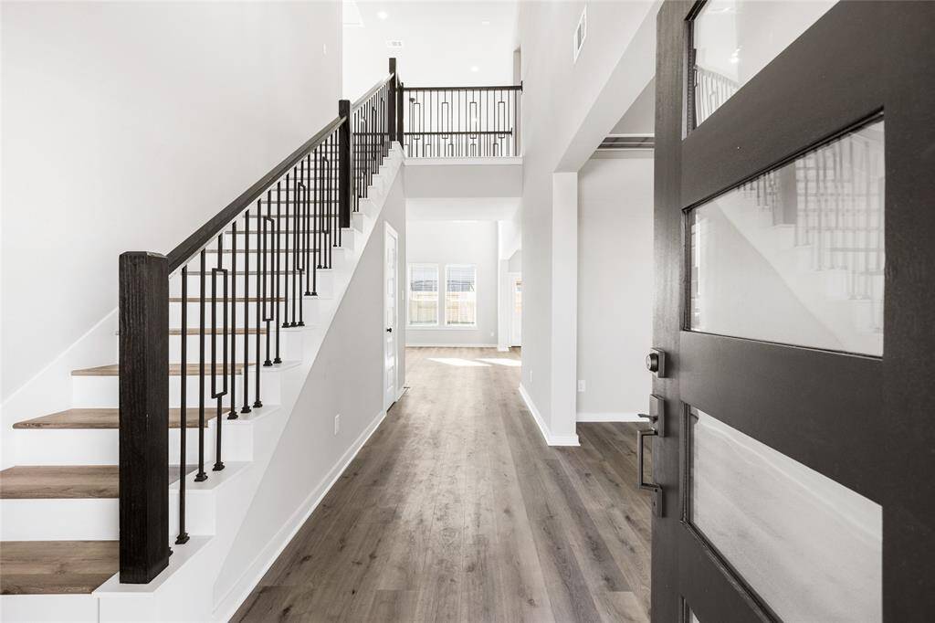 This modern two-story home features a spacious front yard, a double garage, and a sleek exterior design with neutral tones. Located in a suburban neighborhood, it offers a welcoming atmosphere and ample living space.