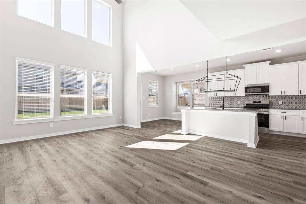 This modern two-story home features a spacious front yard, a double garage, and a sleek exterior design with neutral tones. Located in a suburban neighborhood, it offers a welcoming atmosphere and ample living space.
