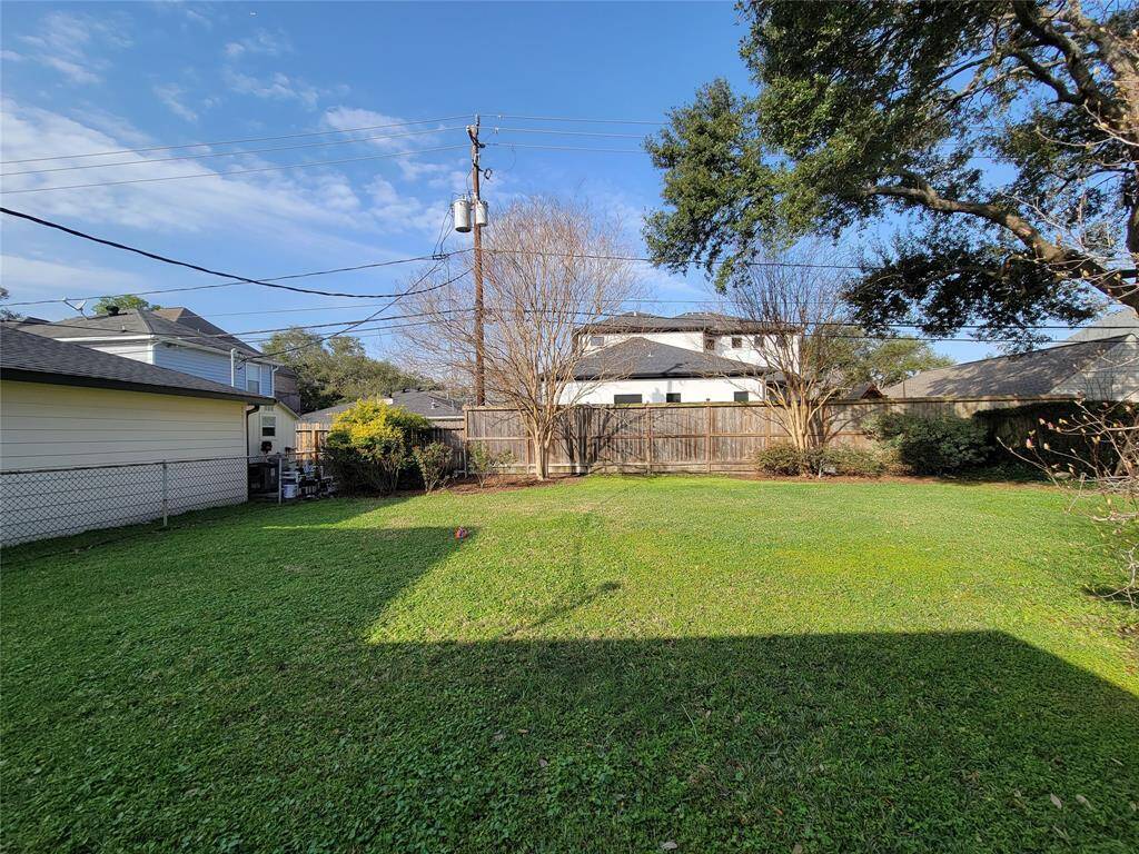 Spacious backyard with lush green grass and mature trees, ideal for outdoor activities and relaxation.