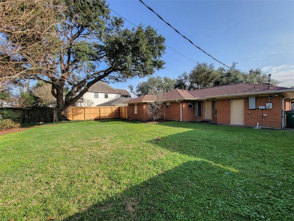 Spacious backyard with a well-maintained lawn, mature trees, and a privacy fence, offering a serene outdoor space for relaxation or entertaining.