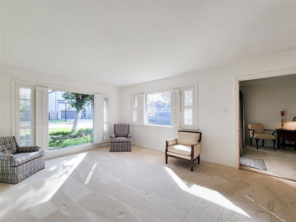 Bright and spacious living room with large windows offering plenty of natural light. Features neutral carpeting and opens to den.