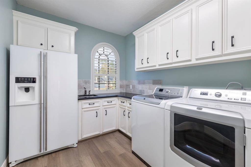 This pristine laundry haven where functionality meets style. With beautifully crafted cabinetry, ample counter space, and natural light pouring through the charming arched window, chores will feel less like a task and more like a breeze.