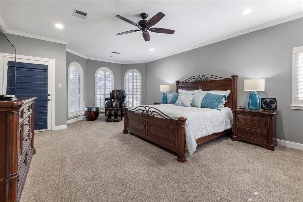 The primary bedroom, where elegance meets comfort. Enjoy the soothing natural light filtering through plantation shutters, perfectly complementing the rich wooden furnishings. Ideal for relaxation, this tranquil space ensures that every morning begins on the right side of the bed.