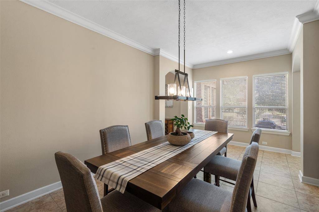 This dining area features a stylish chandelier, the large windows provide ample natural light, and neutral tones create a warm, inviting atmosphere.