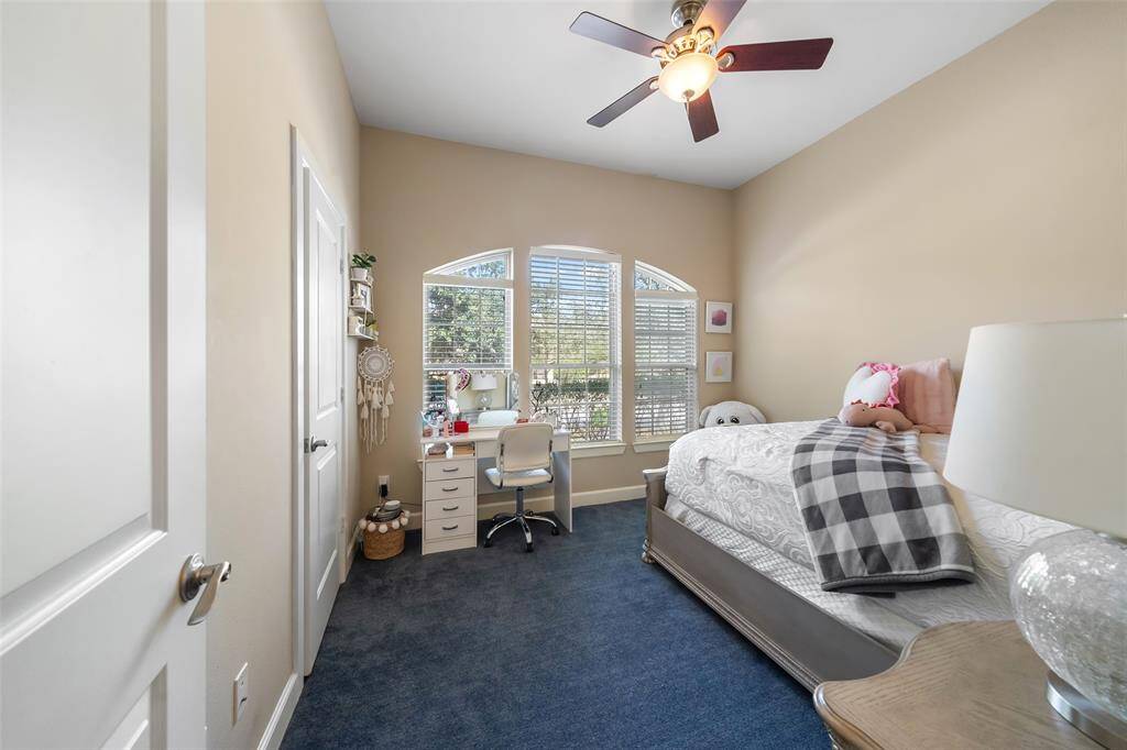 This downstairs secondary bedroom features a large window with ample natural light, a ceiling fan, and neutral walls. Perfect for a child's room or guest space.