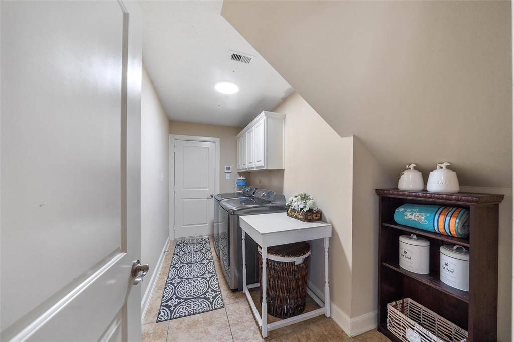 The laundry room with cabinets for storage, and a small sink.