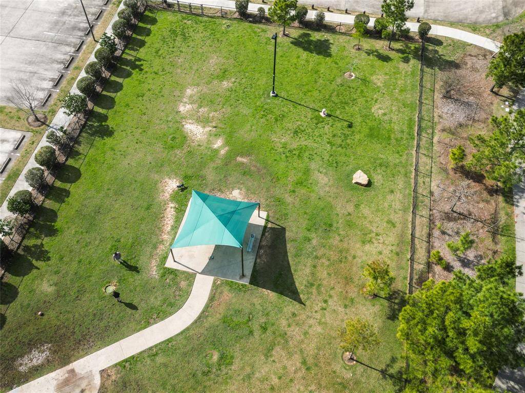 Park area with a shaded pavilion and walking path. Ideal for outdoor activities and relaxation, with surrounding trees and a nearby parking lot.