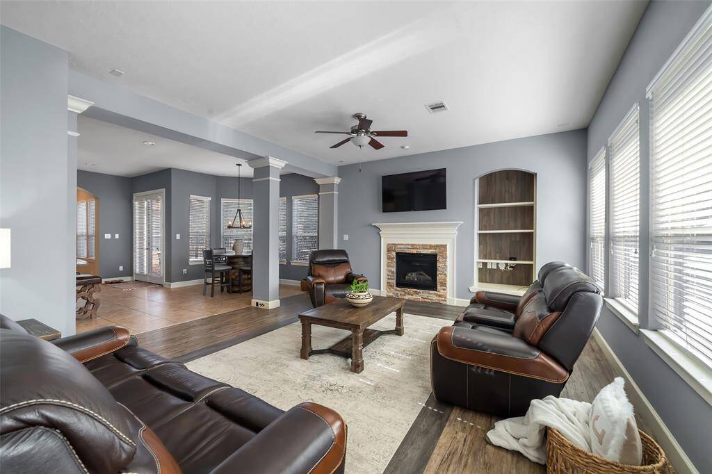 This spacious living area features elegant wood flooring, a cozy fireplace, and abundant natural light from large windows. The open layout seamlessly connects to the dining area, creating an inviting and functional space for entertaining.