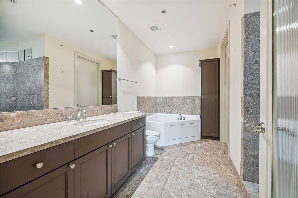 One side of the Primary Bath with expansive stone countertops, soaking tub and step-in shower.