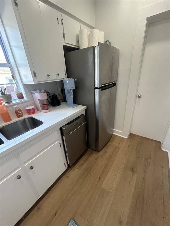 Dishwasher and full refrigerator. Bathroom door to the right.