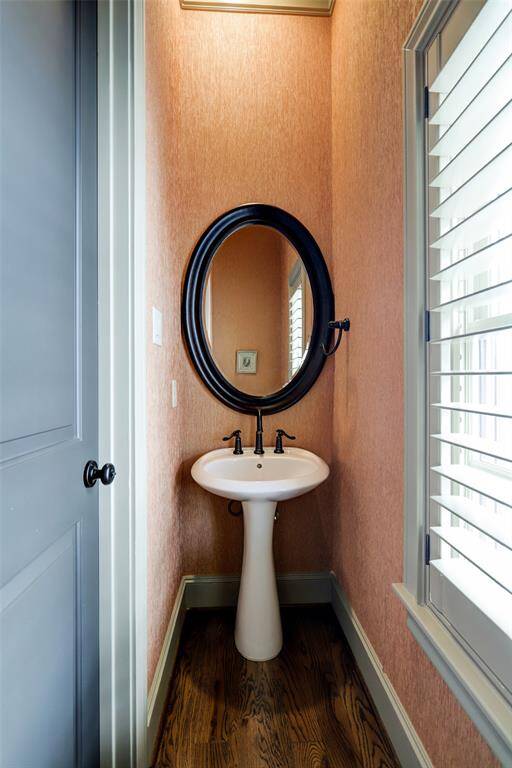 Powder room with pedastal sink on 2nd floor located off living room. Window with plantation shutters provides view to front of home. Oak hardwood floors. Mirror above sink.
