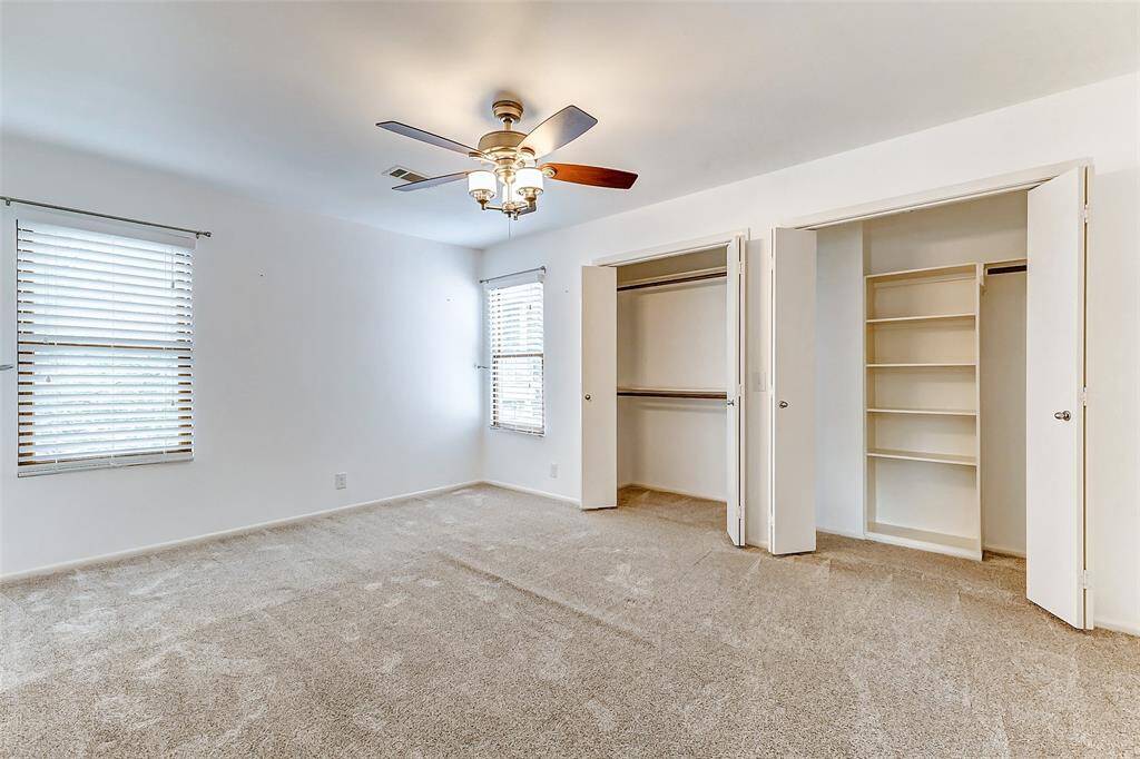 Expansive secondary bedroom with generous closet space, abundant natural light, and stylish Hunter Douglas wood blinds.