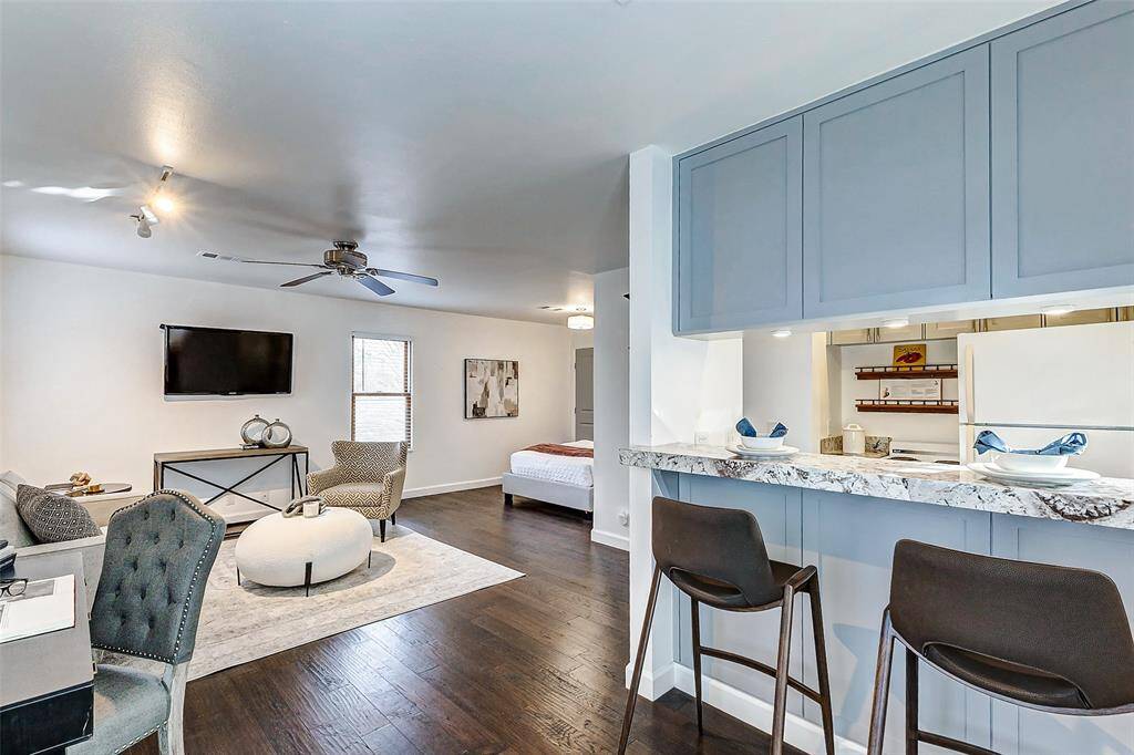 Discover modern living in this updated garage apartment featuring an open-concept design, hardwood floors, and a swiveling TV. Enjoy the cozy seating area and breakfast bar with granite countertops in this bright, inviting space. Perfect for comfortable living.