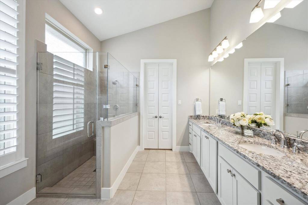 Luxurious primary bath with double sinks, an oversized shower, and a spacious walk-in closet.