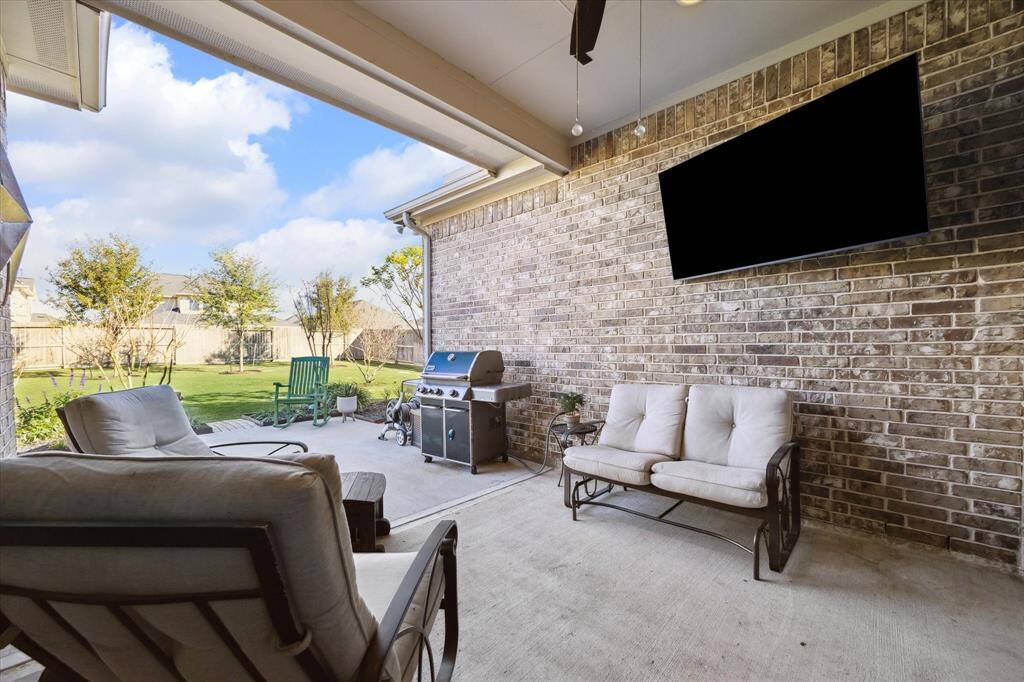 Spacious covered patio perfect for relaxing and entertaining, featuring comfortable seating and a view of the landscaped backyard.