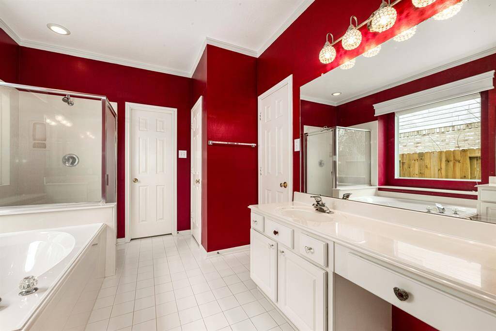 This primary bathroom is definitely move-in ready! Featuring a dark framed walk-in shower with tile surround, separate garden tub for soaking after a long day with custom tile detailing, dark stained cabinets with light countertops, spacious walk-in closet with shelving, high ceilings, custom paint, sleek and dark modern finishes.