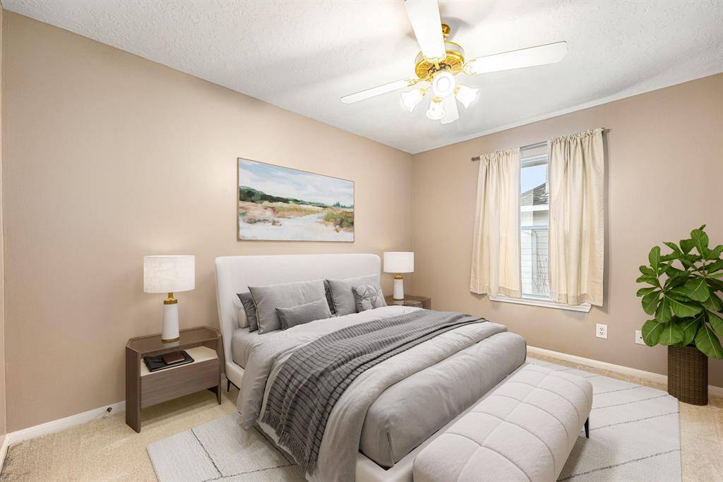 Secondary bedroom features plush carpet, custom paint, a ceiling fan with lighting and a large window providing plenty of natural light. *Virtually Staged