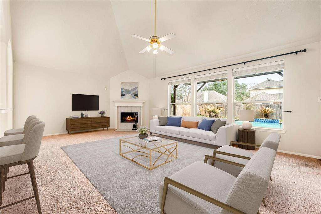 This living room is more like a GREAT room featuring a stunning fireplace with mantel detailing, custom paint, soaring high ceiling, recessed lighting, ceiling fan, and an amazing wall of windows providing a lovely view of your backyard to keep an eye out on the kids or pets playing. *Virtually Staged
