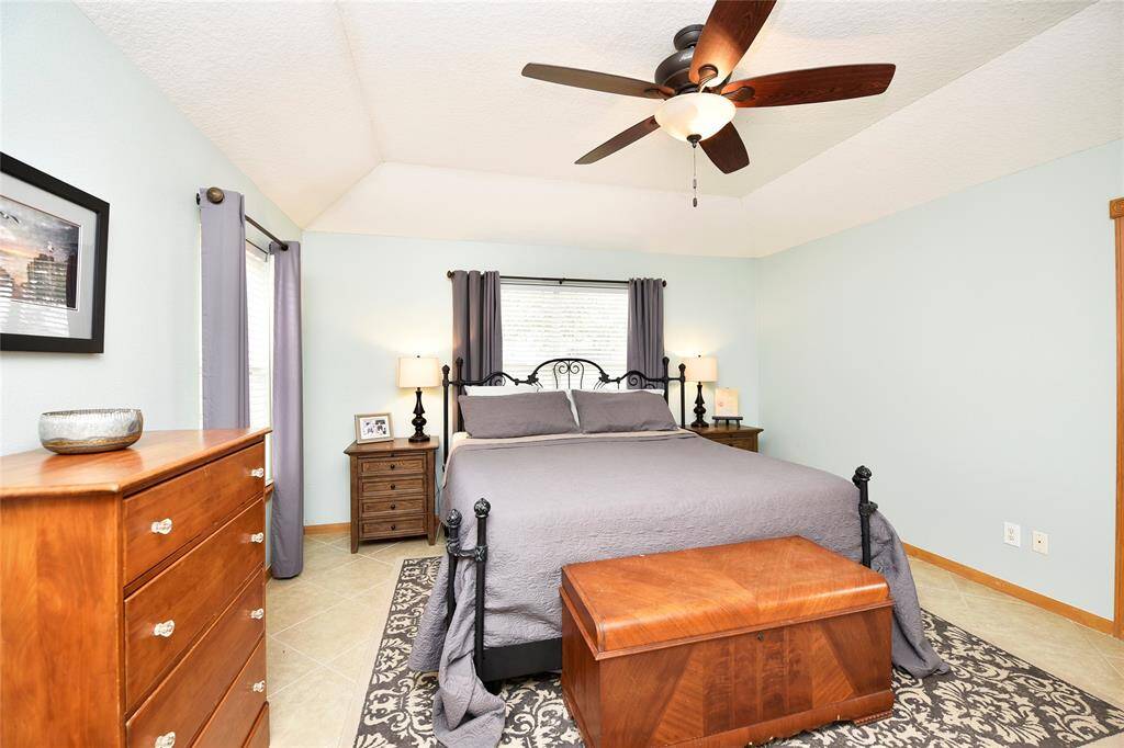Spacious and inviting primary bedroom featuring elegant lighting, a ceiling fan, and warm decor. Perfect for relaxation and comfort.