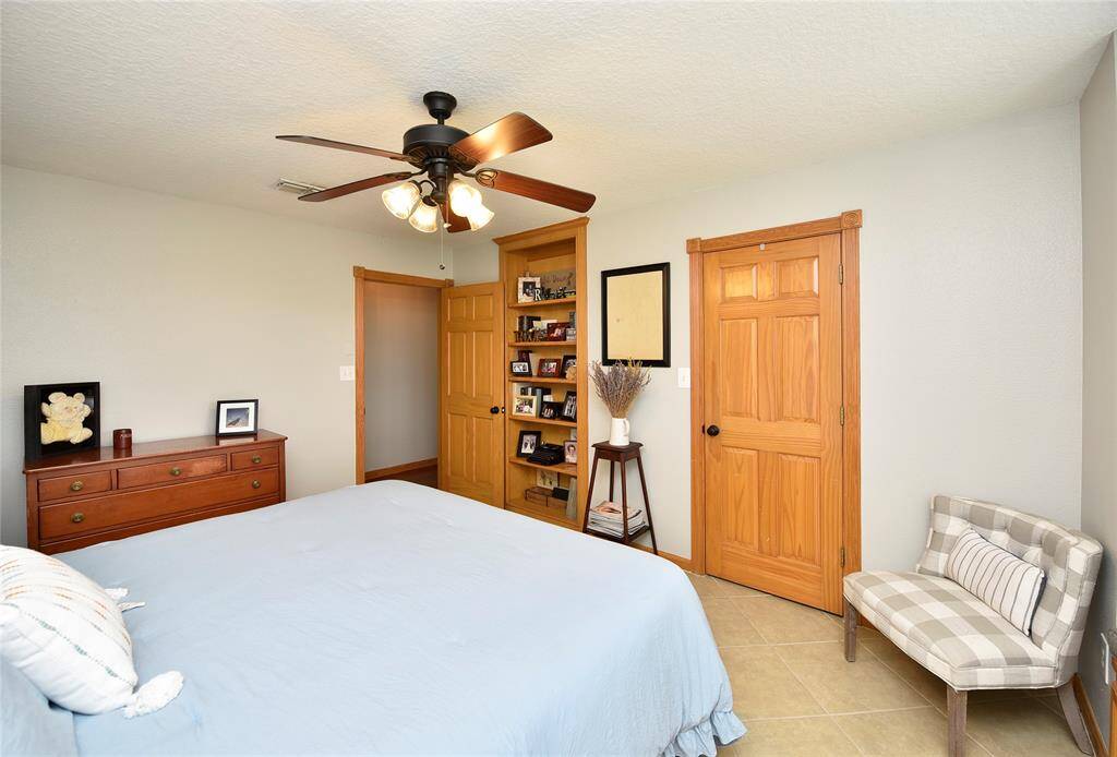 Cozy and inviting, this bedroom features warm wood accents, ample storage, and a stylish ceiling fan, creating a perfect retreat.