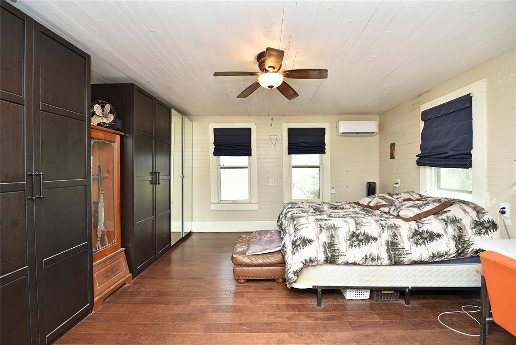 Cozy guest house bedroom featuring ample storage, elegant wood flooring, and abundant natural light.