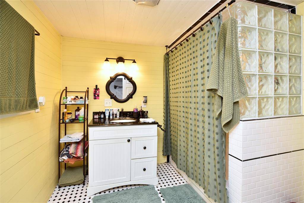 Cozy guest house bathroom featuring a charming vintage vanity, stylish lighting, and a spacious shower.