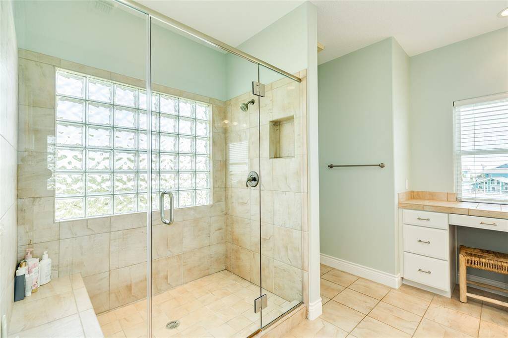 Spacious walk-in shower with loads of natural light and a convenient seat.