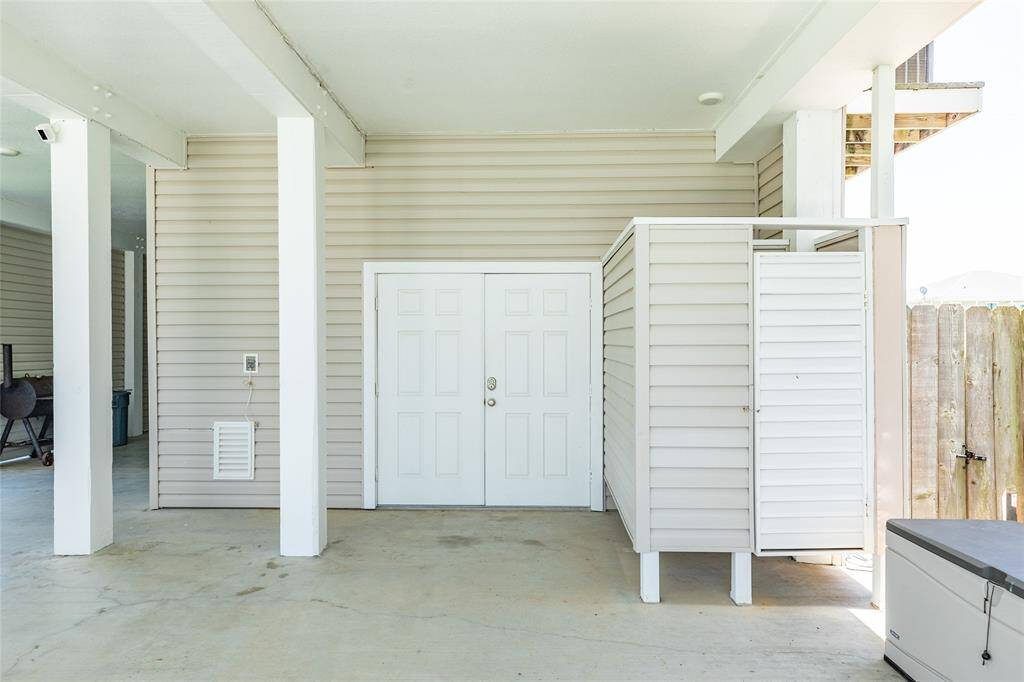 The double doors tuck away loads of storage, the outdoor shower is seen here, and the gate to the left leads to a large secondary parking pad for boats and trailers