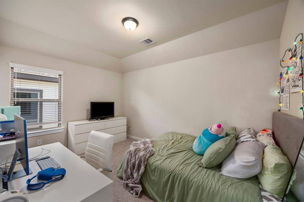 First guest bedroom upstairs with continued high ceilings and walk in closet.