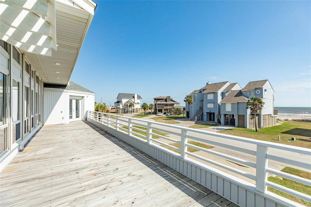 Looking across the deck, notice the beautiful beach views. The French doors in the distance lead to the main-level Primary bedroom.