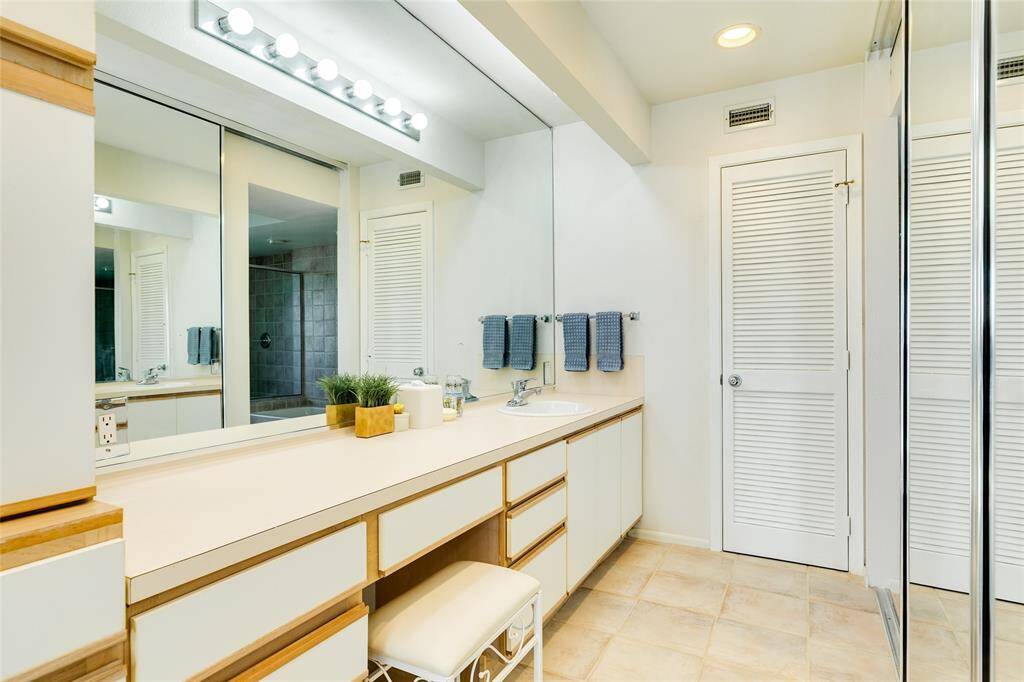 As you enter the primary bath, you notice the large counter space, vanity area, and wall of storage.