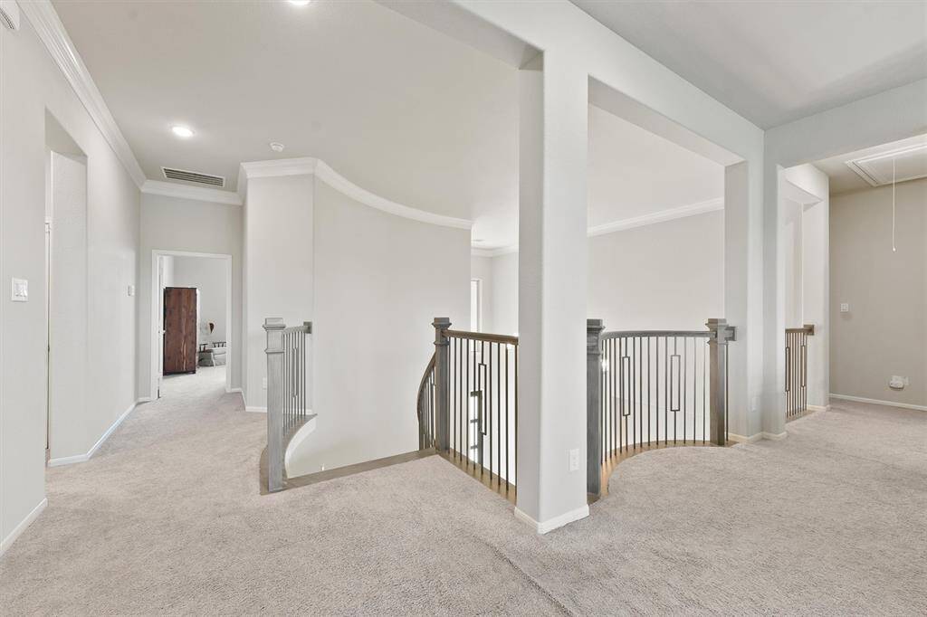 Upstairs hallway with plush carpet, modern railing, and recessed lighting. The space is bright leading to other rooms, offering an open and inviting layout.