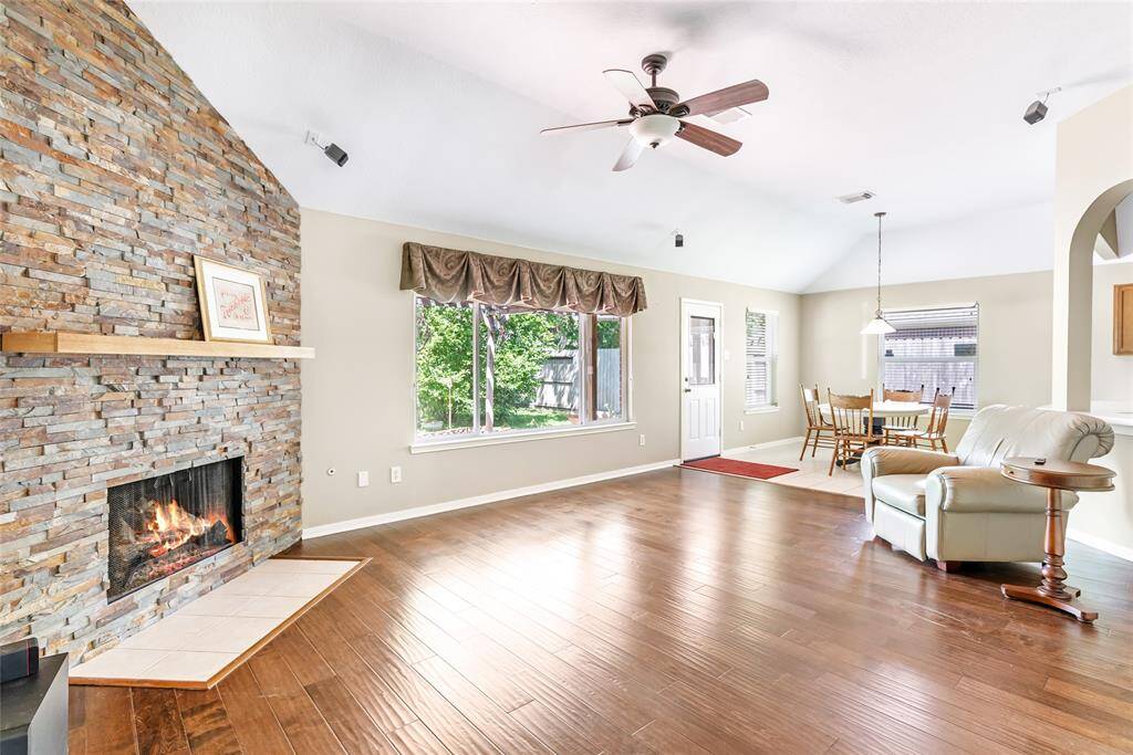 Spacious living room featuring a stunning stacked stone fireplace and great view of the lush backyard