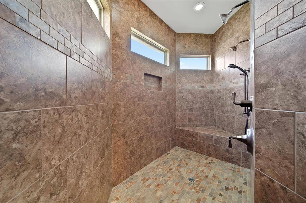 Custom spa like shower with TONS of space to sud up- three shower heads and a bench. Love the natural light!