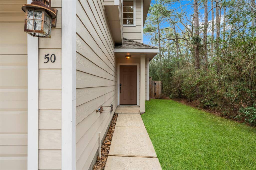 An inviting front porch welcomes your guests with a colorful metal door. The buffer of trees on the right provides privacy.