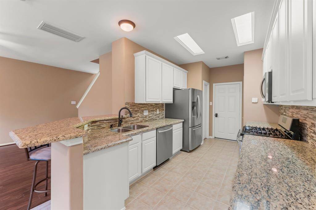 STUNNING GOURMET KITCHEN IS THE HEART OF THIS FINE HOME. It boasts a fresh modern neutral color palette with white cabinetry, exotic granite counter tops, breakfast bar seating, stainless appliances, and tile flooring.