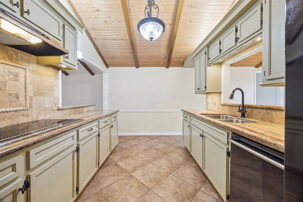 This kitchen has a warm, rustic design with a wooden vaulted ceiling and tile flooring. It includes ample counter space providing a cozy and functional cooking area.