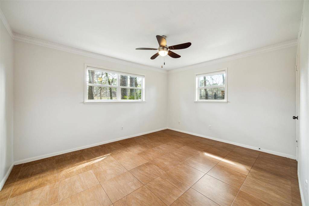 Bright secondary bedroom with neutral walls and a ceiling fan.