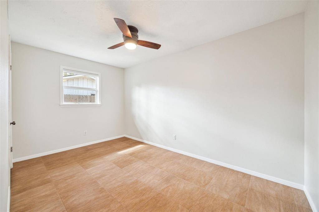 This secondary bedroom with light walls and natural light and is equipped with a modern ceiling fan. Ideal for a cozy bedroom or office space.