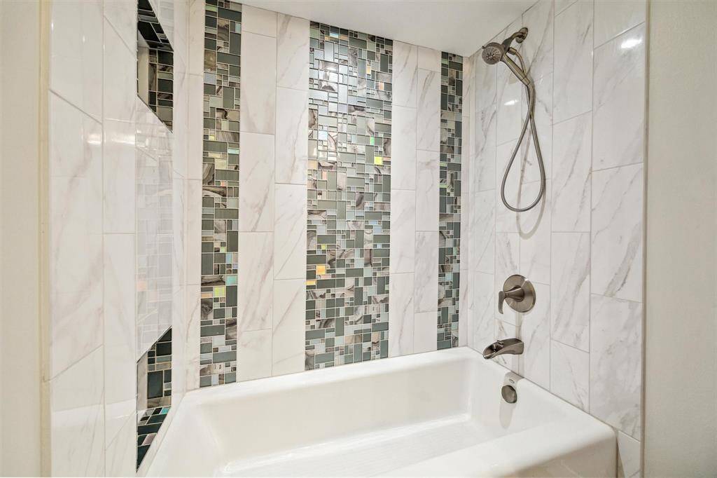Mosaic tiles accent this tiled shower in the secondary bathroom.