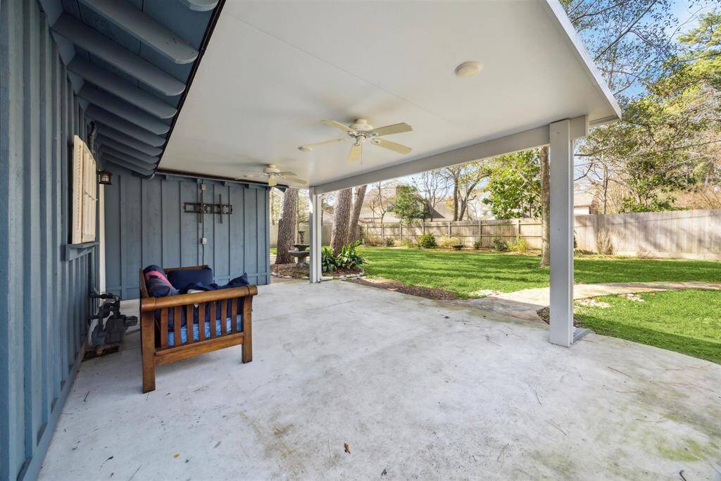 Another view of covered patio with ceiling fans, ideal for outdoor relaxation. It overlooks a well-maintained, fenced backyard with lush green grass, providing a private and serene environment.