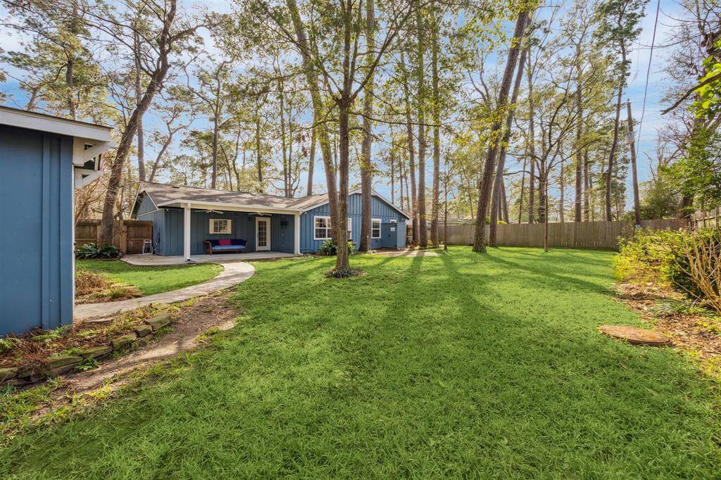 Well-maintained backyard, surrounded by tall trees. A paved pathway and 2 patio areas, perfect for outdoor relaxation and entertaining.